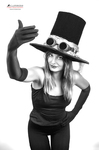 Retrato en blanco y negro de mujer adulta con sombrero de copa alto, posando con una mano levantada en actitud teatral.
