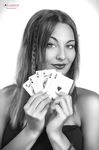 Retrato en blanco y negro de mujer adulta sosteniendo varias cartas o naipes cerca del rostro, con gesto juguetón.
