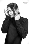 Retrato en blanco y negro de mujer adulta con jersey oscuro, sonriendo mientras se toca el rostro con ambas manos.