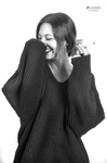 Retrato en blanco y negro de mujer adulta riendo, medio escondida tras las mangas de un jersey amplio.