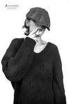 Retrato en blanco y negro de mujer adulta con boina y jersey oscuro, tocándose el rostro con gesto tímido.