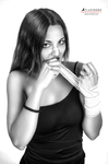 Retrato en blanco y negro de mujer adulta con top oscuro, sujetando con los labios una cinta o tira fina.