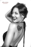 Retrato en blanco y negro de mujer adulta girada de espaldas, sonriendo con un tatuaje visible en el hombro.