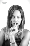 Retrato en blanco y negro de mujer adulta con un dedo apoyado sobre los labios en gesto de silencio.