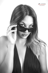 Retrato en blanco y negro de mujer adulta bajando ligeramente las gafas de sol para mirar a cámara.