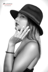 Retrato en blanco y negro de mujer adulta con sombrero oscuro, posando de perfil con una mano en el cuello.