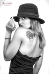 Retrato en blanco y negro de mujer adulta de espaldas parciales, girando el rostro con sombrero oscuro.