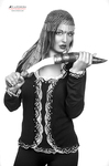 Retrato en blanco y negro de mujer adulta con vestuario tipo corsé, sosteniendo una daga u objeto puntiagudo en pose teatral.
