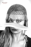 Primer plano en blanco y negro de mujer adulta con tocado o velo de cuentas cubriendo la frente y un cuchillo horizontal delante del rostro.