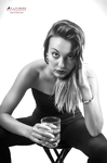 Retrato en blanco y negro de mujer adulta inclinada hacia delante, sosteniendo un vaso con ambas manos.