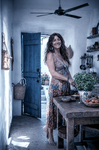 Alina junto a una puerta azul de Casa Salobre, iluminada por la luz fría que entra desde el exterior.