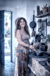 Alina cocinando en la cocina antigua de Casa Salobre, rodeada de utensilios, platos y objetos domésticos.