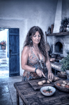 Alina sentada en la cocina de Casa Salobre, preparando comida sobre una mesa de madera antigua.