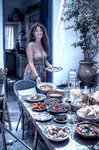 Alina de pie junto a una mesa servida con platos, frutas y comida en Casa Salobre.