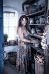 Alina junto a una alacena antigua de Casa Salobre, rodeada de platos, utensilios y memoria doméstica.