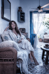 Alina descansando en un sofá antiguo de Casa Salobre, vestida de blanco y rodeada de luz doméstica.