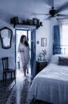 Alina en el dormitorio blanco y azul de Casa Salobre, junto a una cama antigua y una ventana luminosa.