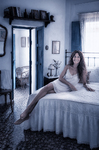 Alina recostada sobre la cama blanca de Casa Salobre, iluminada por la luz que entra desde la ventana.