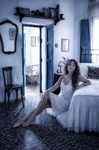 Alina sentada en el suelo del dormitorio de Casa Salobre, junto a la cama y bajo una luz suave.