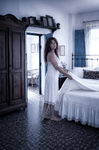 Alina arreglando las sábanas blancas de una cama antigua en el dormitorio de Casa Salobre.
