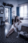 Alina sentada descalza en el suelo de una habitación antigua de Casa Salobre, junto a la cama.