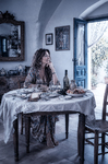 Alina sentada en una mesa antigua de Casa Salobre, en una escena doméstica de calma y memoria.