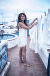 Alina tendiendo ropa blanca en la azotea mediterránea de Casa Salobre, bajo la luz del mar.
