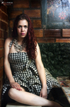 Marina sentada sobre la mesa de billar, con vestido de cuadros y fondo de madera en tonos cálidos.