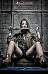 Ros Vélez sentada en un entorno industrial, con ropa de camuflaje y pose de carácter fuerte.