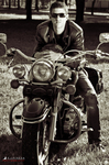 Gustavo posa sobre una motocicleta clásica, con gafas de sol y estética vintage.