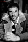 Retrato en blanco y negro de Gustavo con abrigo, mirada directa y expresión intensa.