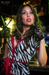 Esther posa con blusa de estampado animal y pañuelo rojo, mirando hacia arriba bajo luces de colores.