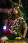 Esther sentada en una barra de bar, con luces de colores y pose relajada.