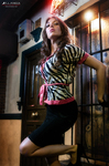 Esther posa de pie en la puerta de un local, con blusa estampada y pañuelo rojo.