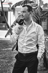 Manuel posa en blanco y negro con camisa blanca y pantalón oscuro, en actitud relajada.