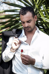 Manuel enciende un cigarro con camisa blanca, en un retrato exterior de luz natural.