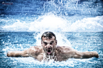 Manuel nadando en una piscina azul, captado de frente entre salpicaduras de agua.