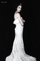 Modelo femenina vestida de blanco, de pie sobre fondo negro, en una imagen de estilo nupcial.