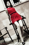 Modelo femenina con vestido rojo posando en una escalera o estructura metálica.