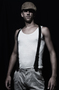 Modelo masculino con camiseta de tirantes sobre fondo negro, en un retrato de estudio.