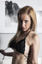 Modelo rubia sentada con lencería negra, en un retrato íntimo de interior.