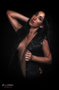 Modelo femenina posando con ropa negra sobre fondo oscuro.