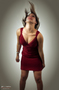 Modelo femenina con vestido rojo posando de pie sobre fondo claro.