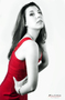 Modelo femenina con vestido rojo sentada, en una imagen en blanco y negro.