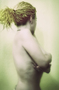 Modelo femenina en desnudo artístico de perfil, con fondo verde suave.