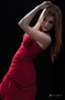 Modelo femenina con vestido rojo, posando con los brazos levantados.