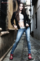Modelo femenina sentada en un umbral, con vaqueros y zapatos rojos.