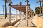 Estructura de madera en la playa de Carboneras, con arena clara, palmeras y luz mediterránea.