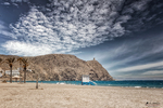 Playa de Carboneras con montaña junto al mar, arena clara y cielo dramático sobre la costa de Almería.