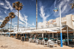 Terrazas del paseo marítimo de Carboneras con palmeras, banderas y ambiente costero en Almería.